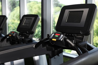Photo of Many modern treadmills near window in gym, closeup