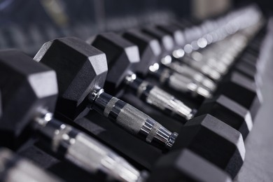 Photo of Different dumbbells in gym, closeup. Sport equipment