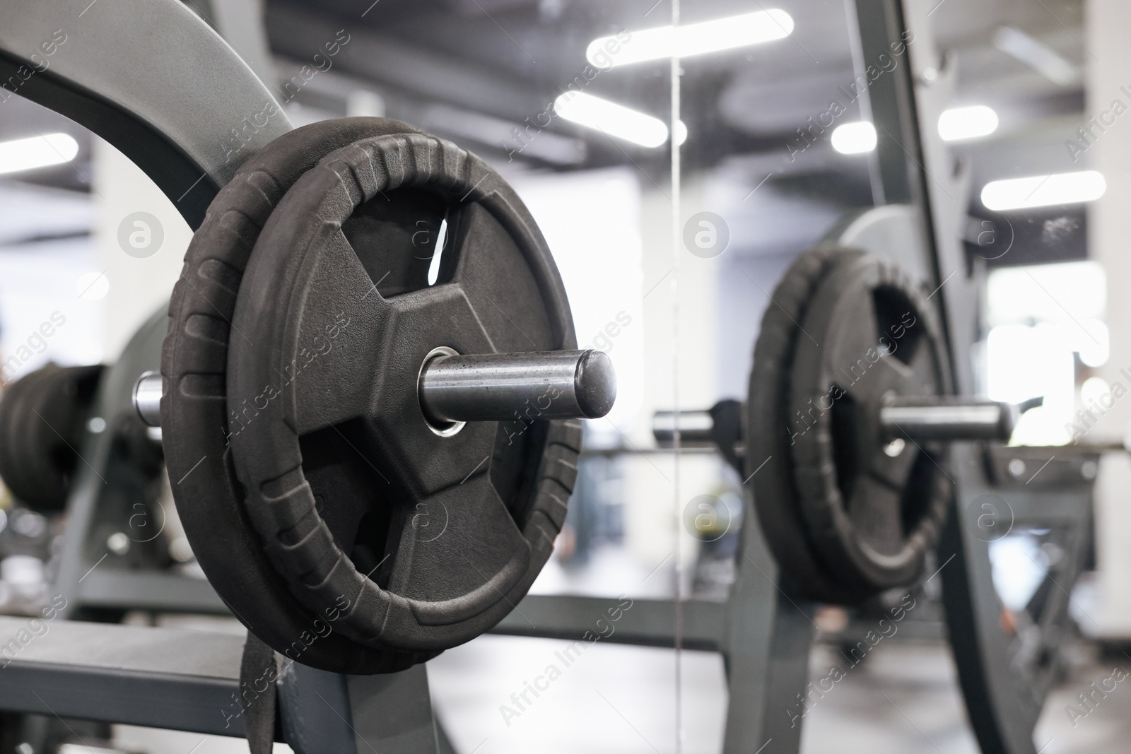 Photo of Stand with barbell disc near mirror in gym, closeup. Space for text