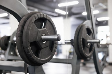 Photo of Stand with barbell disc near mirror in gym, closeup. Space for text