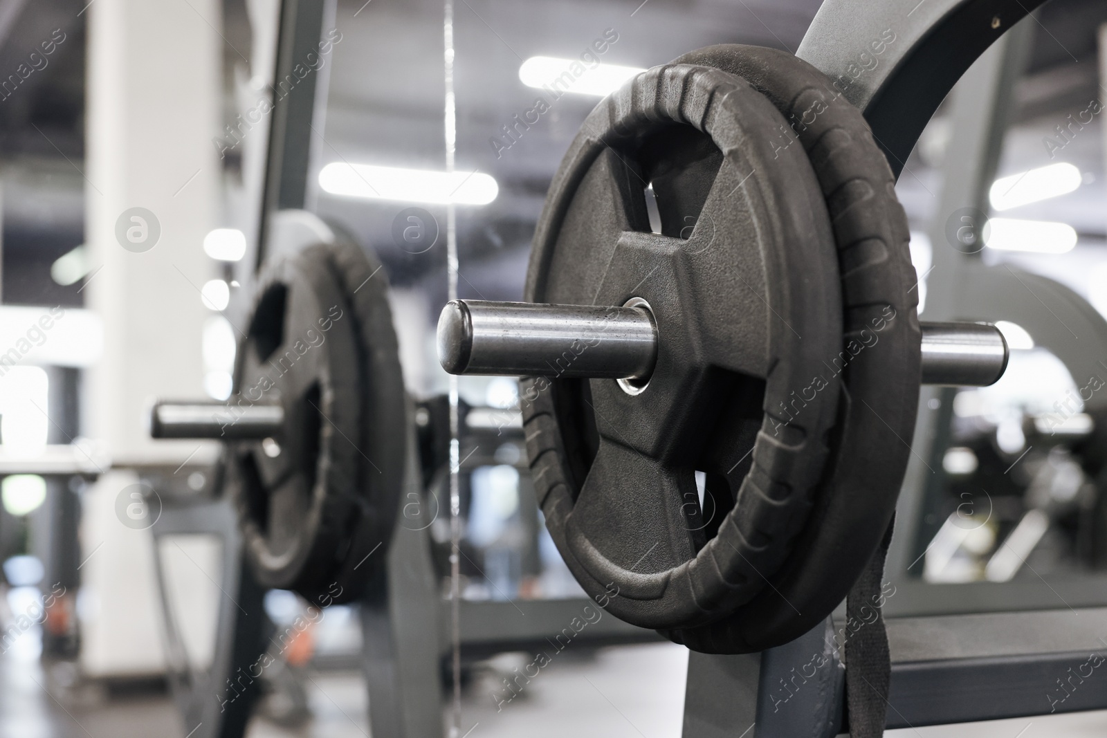 Photo of Stand with barbell disc near mirror in gym, closeup. Space for text