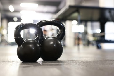 Photo of Black kettlebells on floor in gym, closeup. Space for text