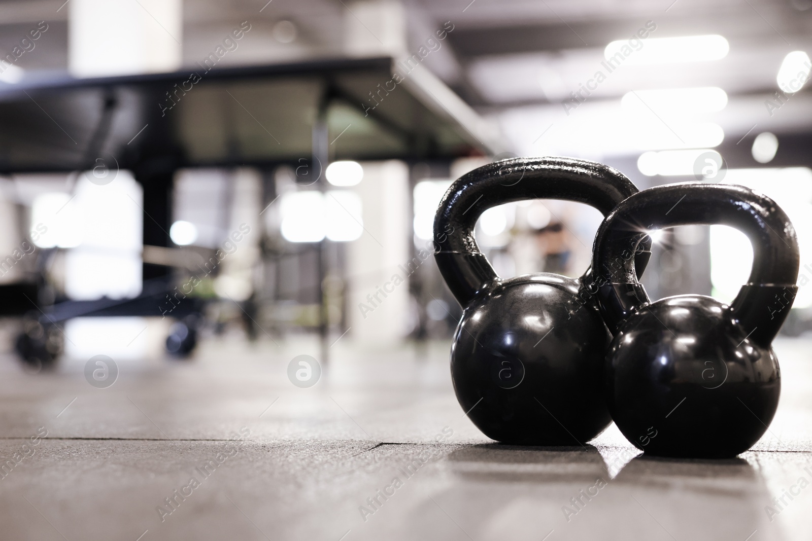 Photo of Black kettlebells on floor in gym, closeup. Space for text