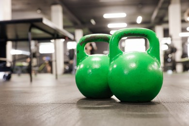 Photo of Green kettlebells on floor in gym, closeup. Space for text