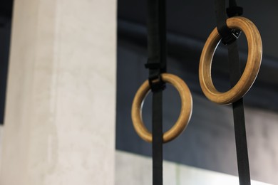 Photo of Gymnastic rings hanging in gym, low angle view. Space for text