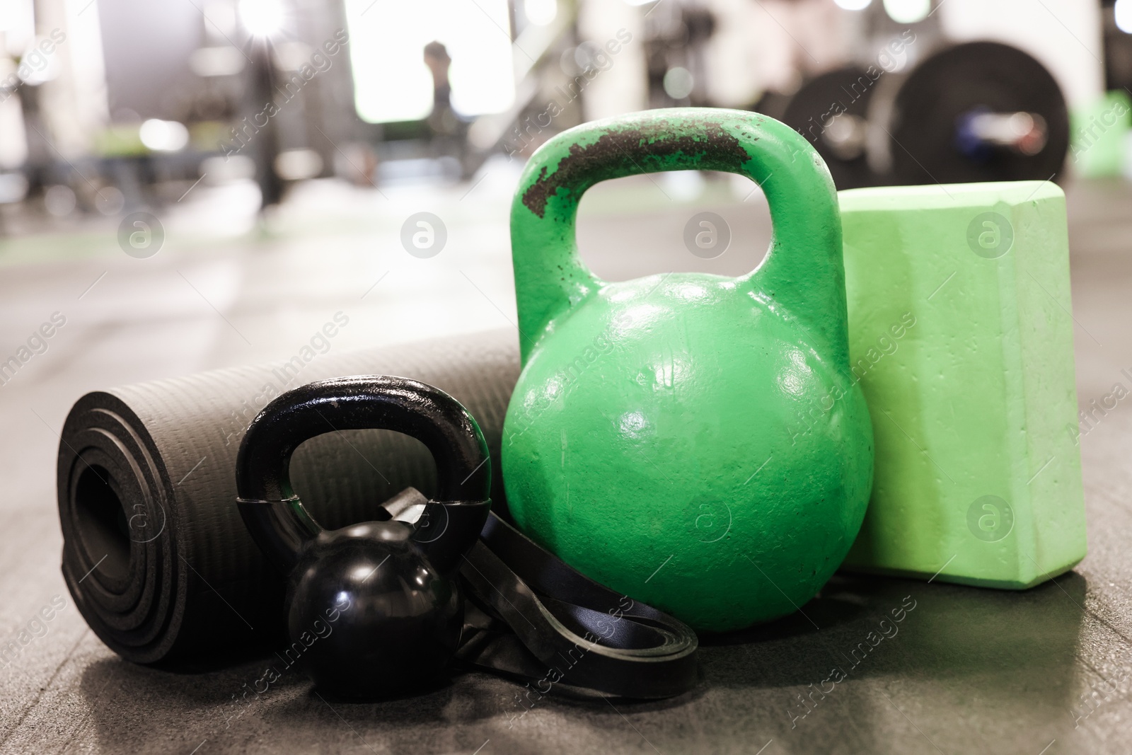 Photo of Kettlebells and other sport equipment on floor in gym, closeup