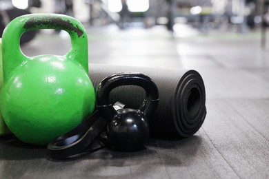 Photo of Kettlebells and other sport equipment on floor in gym, closeup