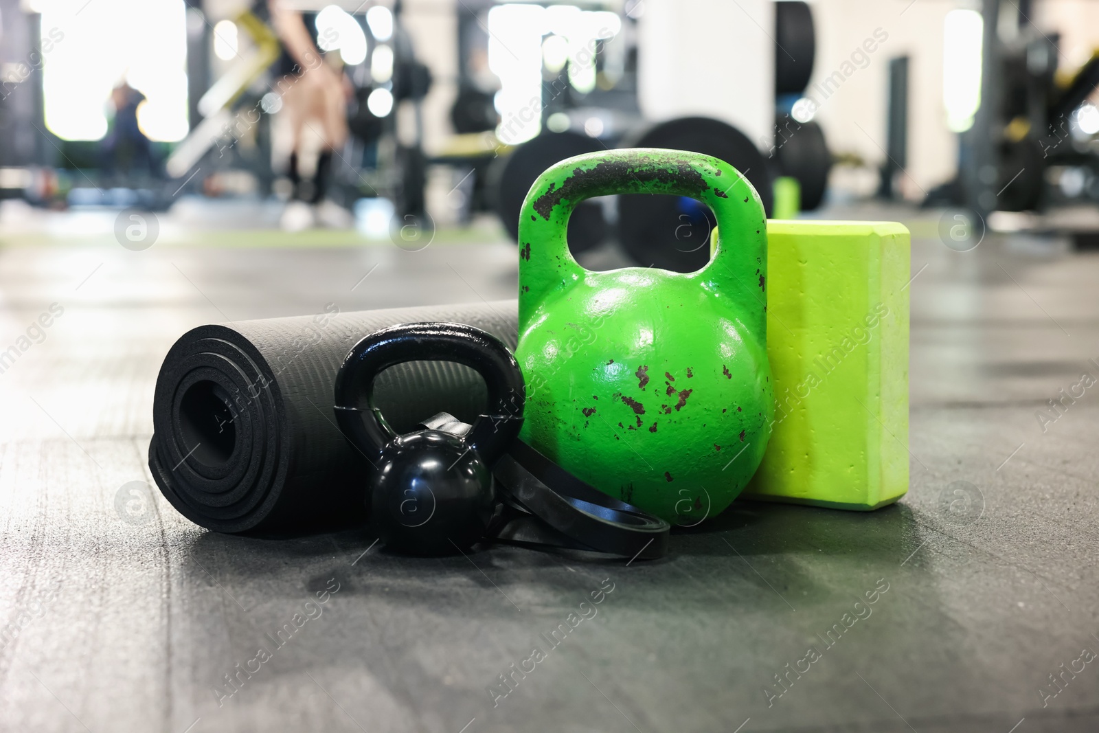 Photo of Kettlebells and other sport equipment on floor in gym, closeup