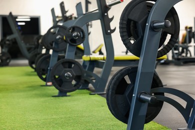 Photo of Stands with barbell discs in gym. Sport equipment