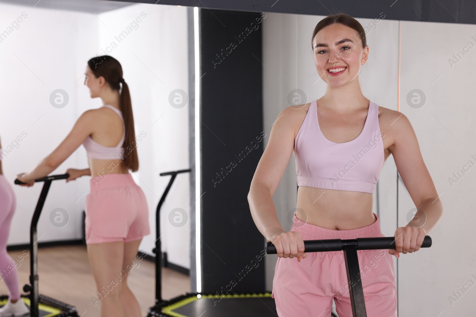 Smiling woman on mini exercise trampoline near mirror in fitness studio. Space for text Photo of Smiling woman on mini exercise trampoline near mirror in fitness studio. Space for text