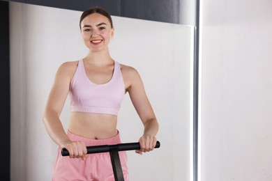 Photo of Smiling woman on mini exercise trampoline near mirror in fitness studio. Space for text