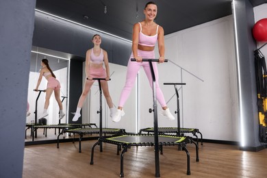 Photo of Smiling women jumping on mini exercise trampolines in fitness studio, low angle view