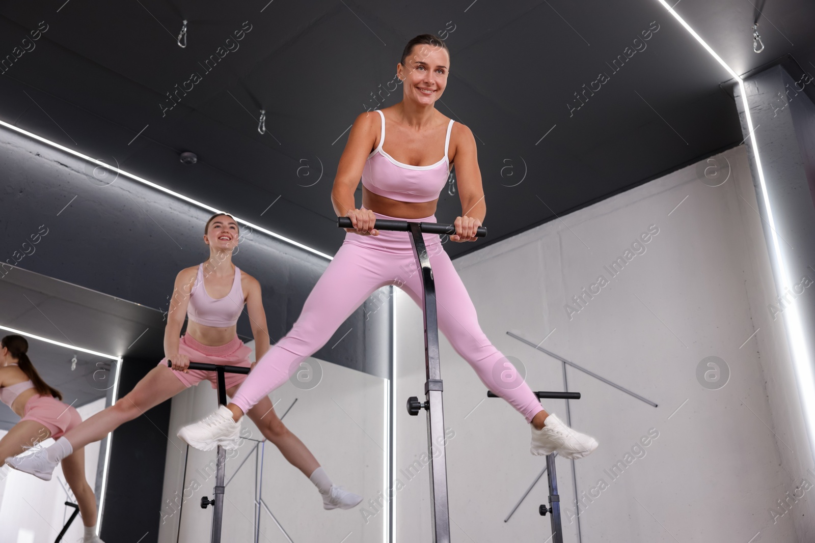 Smiling women jumping on mini exercise trampolines in fitness studio, low angle view Photo of Smiling women jumping on mini exercise trampolines in fitness studio, low angle view