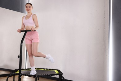 Photo of Smiling woman on mini exercise trampoline in fitness studio, low angle view. Space for text