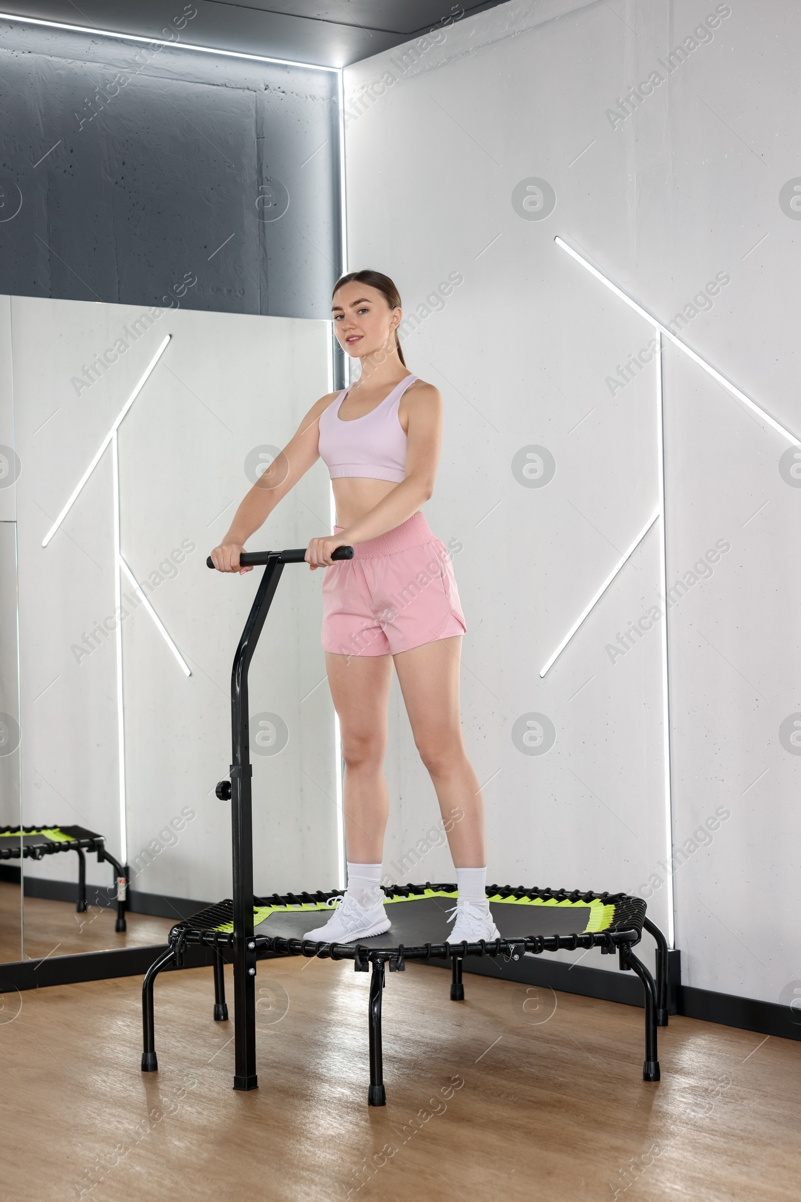 Young woman on mini exercise trampoline near mirror in fitness studio Photo of Young woman on mini exercise trampoline near mirror in fitness studio