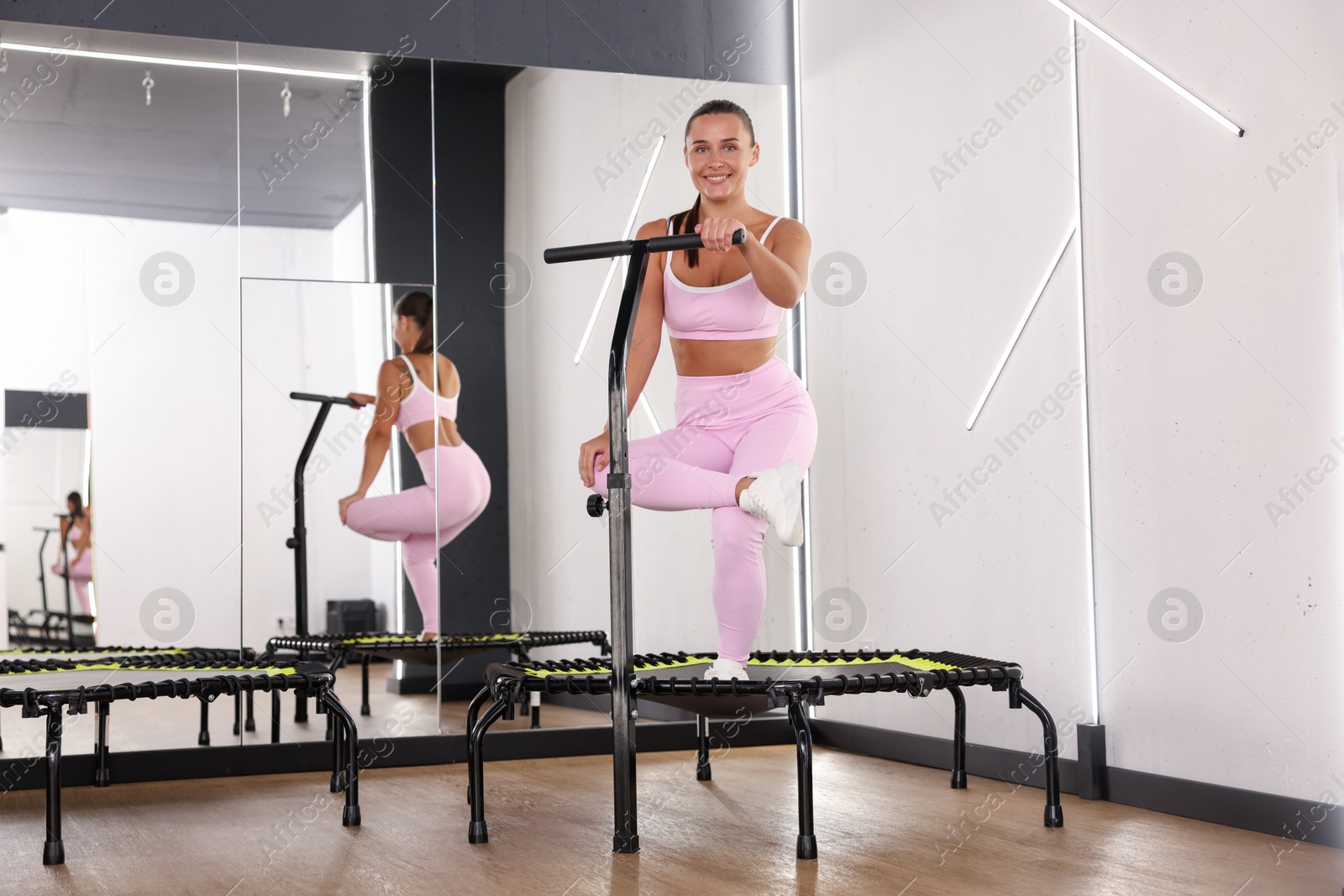 Smiling woman training on mini exercise trampoline near mirror in fitness studio Photo of Smiling woman training on mini exercise trampoline near mirror in fitness studio