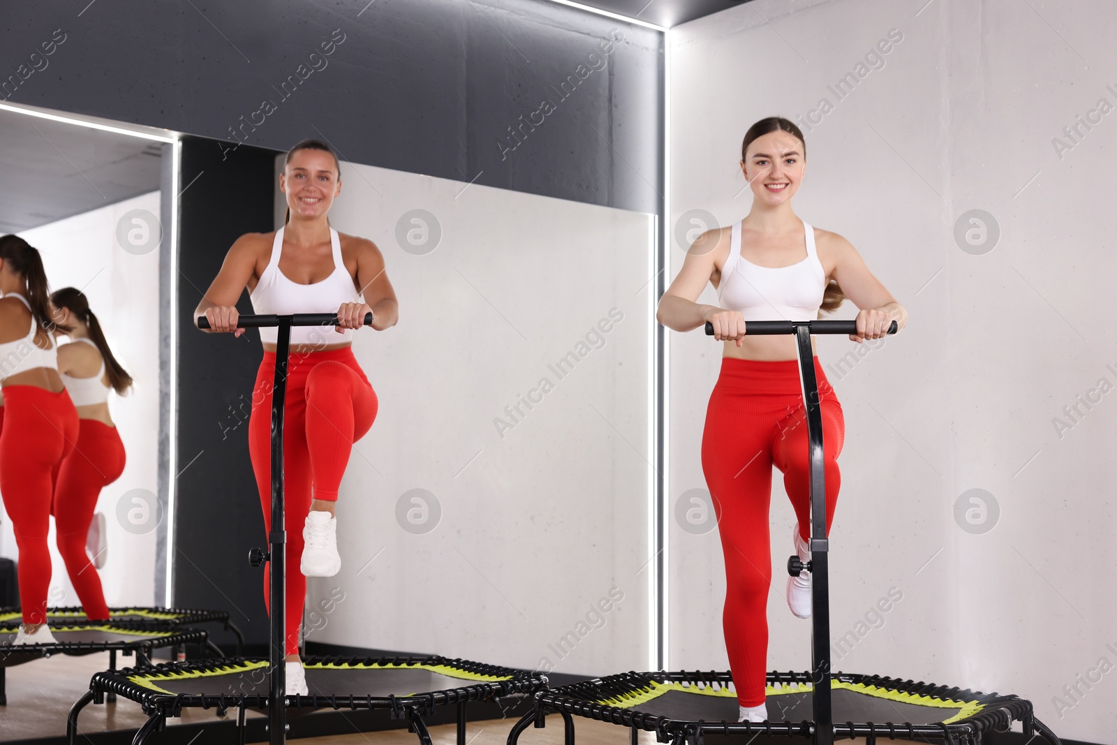 Photo of Smiling women training on mini exercise trampolines in fitness studio, low angle view