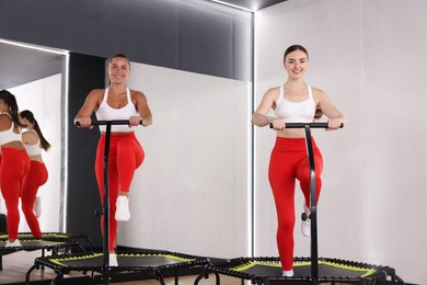 Photo of Smiling women training on mini exercise trampolines in fitness studio, low angle view