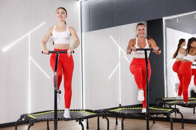 Photo of Smiling women training on mini exercise trampolines in fitness studio, low angle view