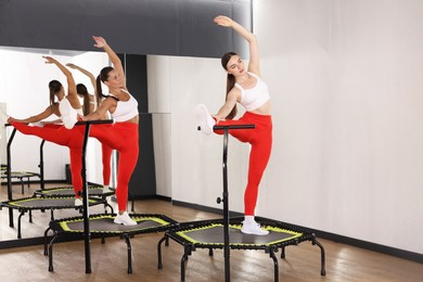 Photo of Young women training on mini exercise trampolines near mirror in fitness studio