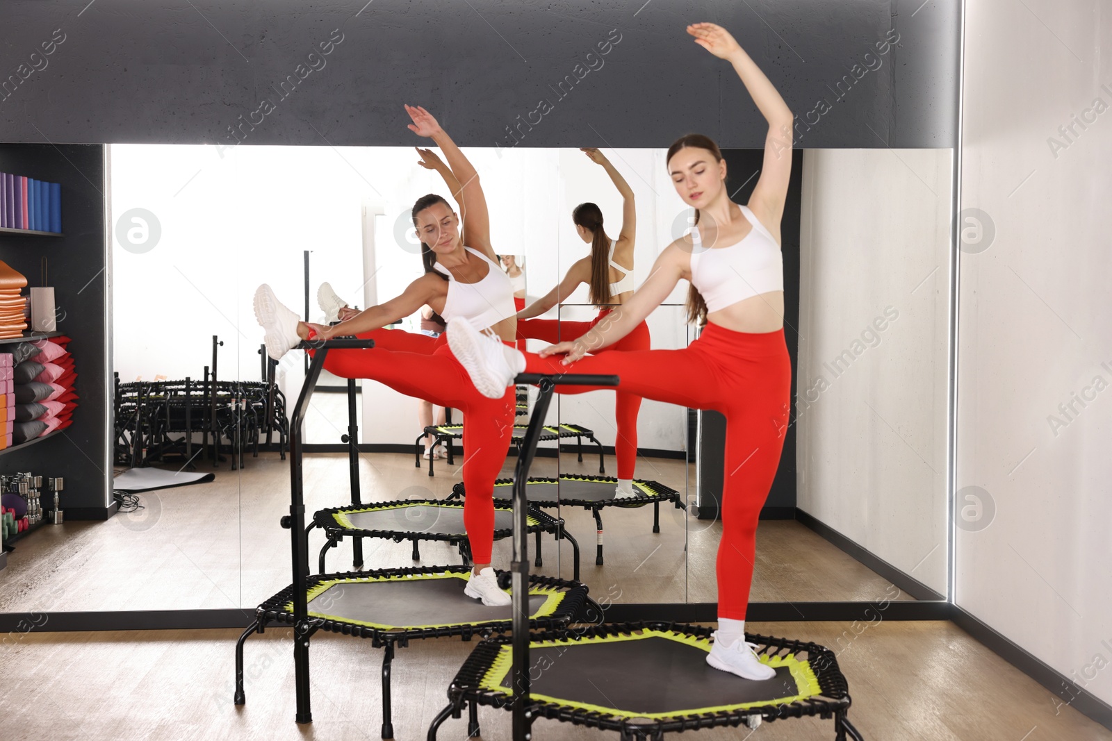 Young women training on mini exercise trampolines near mirror in fitness studio Photo of Young women training on mini exercise trampolines near mirror in fitness studio