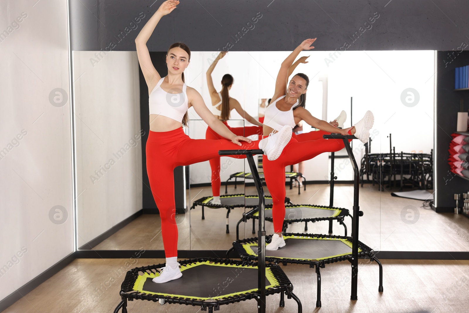 Young women training on mini exercise trampolines near mirror in fitness studio Photo of Young women training on mini exercise trampolines near mirror in fitness studio