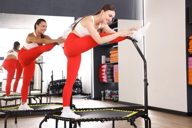 Photo of Smiling women stretching on mini exercise trampolines in fitness studio