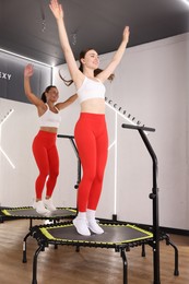 Photo of Smiling women jumping on mini exercise trampolines in fitness studio, low angle view