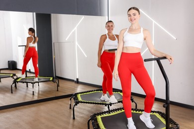 Photo of Smiling women on mini exercise trampolines in fitness studio. Space for text
