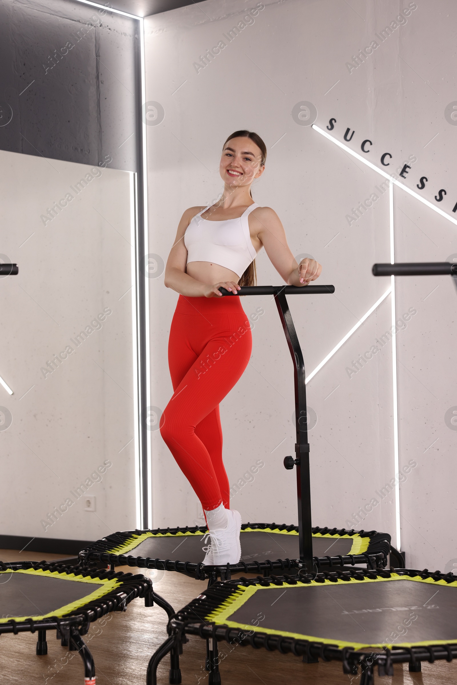 Smiling woman on mini exercise trampoline in fitness studio, low angle view Photo of Smiling woman on mini exercise trampoline in fitness studio, low angle view