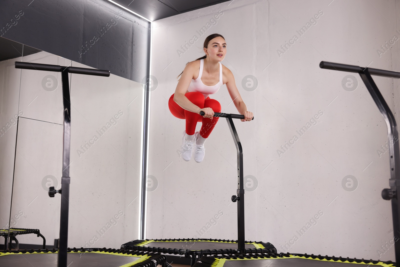 Young woman jumping on mini exercise trampoline in fitness studio, low angle view Photo of Young woman jumping on mini exercise trampoline in fitness studio, low angle view