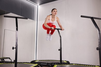 Photo of Young woman jumping on mini exercise trampoline in fitness studio, low angle view