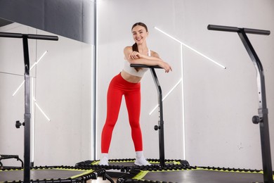 Photo of Smiling woman on mini exercise trampoline in fitness studio, low angle view