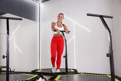 Photo of Smiling woman on mini exercise trampoline in fitness studio, low angle view