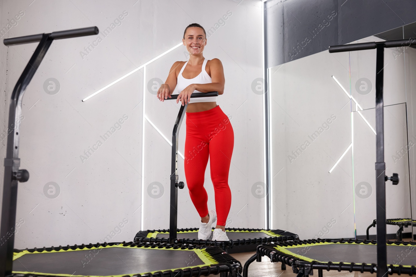 Smiling woman on mini exercise trampoline in fitness studio, low angle view Photo of Smiling woman on mini exercise trampoline in fitness studio, low angle view