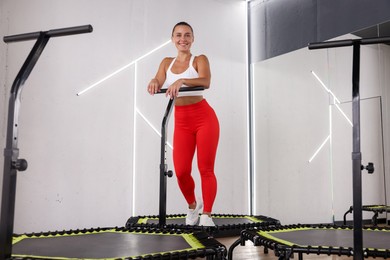 Photo of Smiling woman on mini exercise trampoline in fitness studio, low angle view