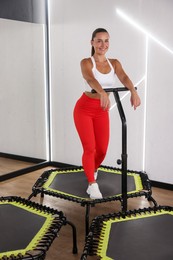 Photo of Smiling woman on mini exercise trampoline in fitness studio