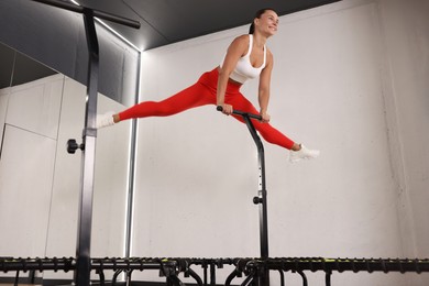 Photo of Smiling woman jumping on mini exercise trampoline in fitness studio, low angle view