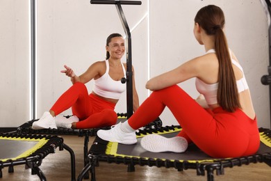 Photo of Smiling women talking on mini exercise trampolines in fitness studio