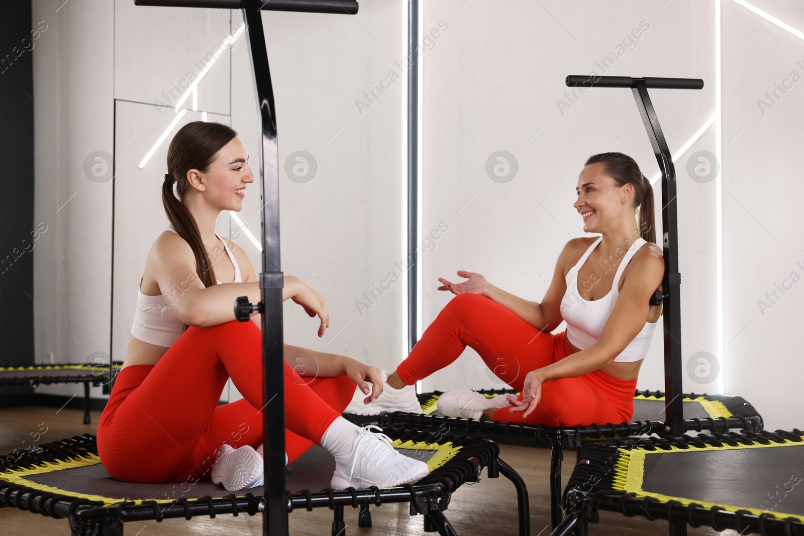 Photo of Smiling women talking on mini exercise trampolines in fitness studio