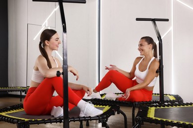 Photo of Smiling women talking on mini exercise trampolines in fitness studio