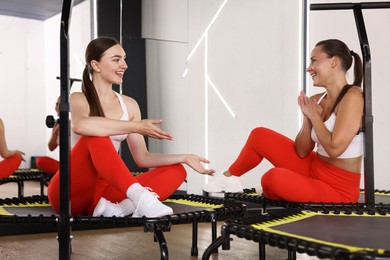 Photo of Smiling women talking on mini exercise trampolines in fitness studio