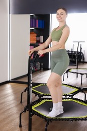 Photo of Smiling woman on mini exercise trampoline in fitness studio