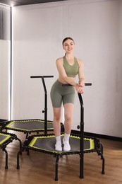 Photo of Smiling woman on mini exercise trampoline in fitness studio