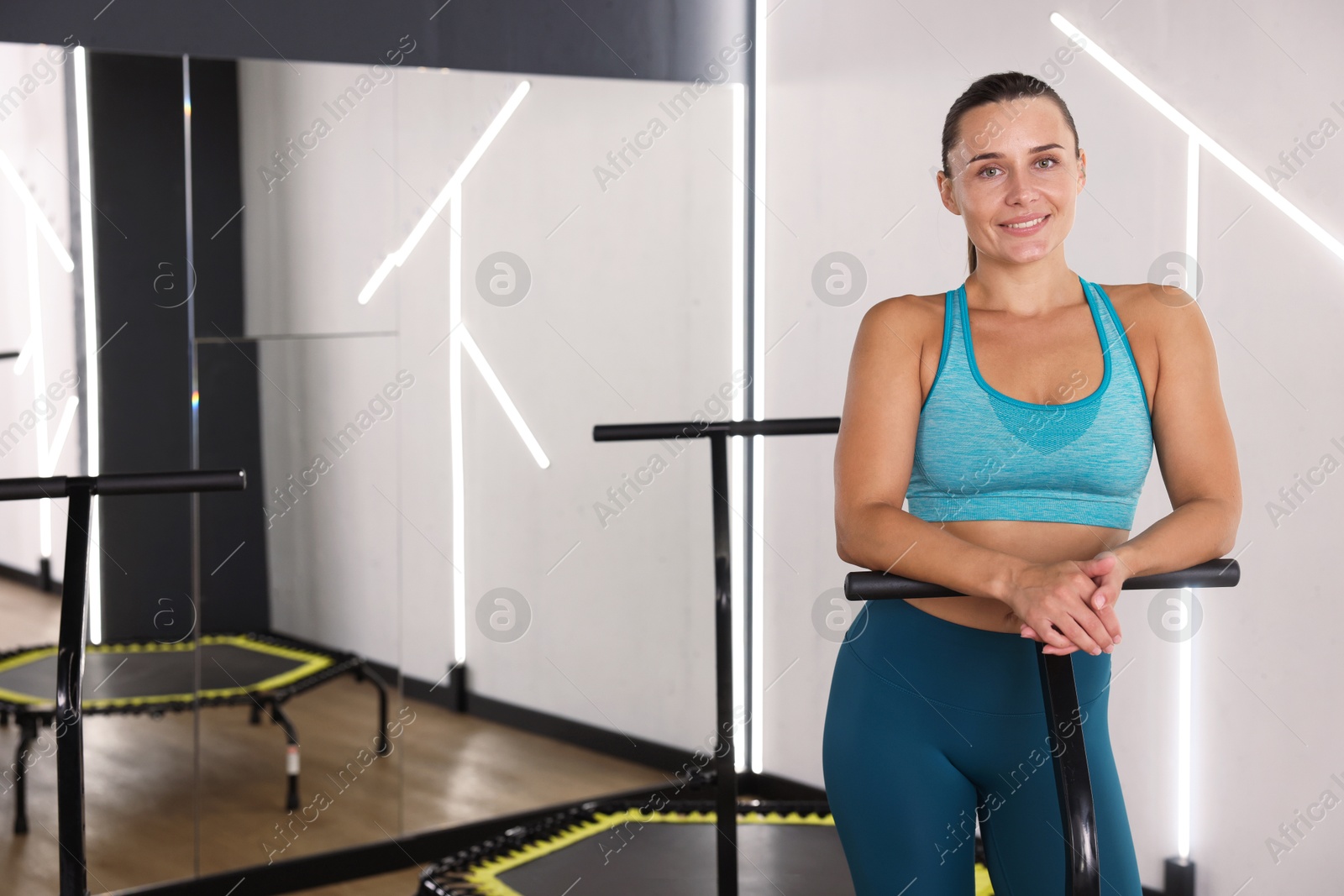 Smiling woman on mini exercise trampoline in fitness studio. Space for text Photo of Smiling woman on mini exercise trampoline in fitness studio. Space for text