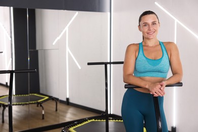 Photo of Smiling woman on mini exercise trampoline in fitness studio. Space for text