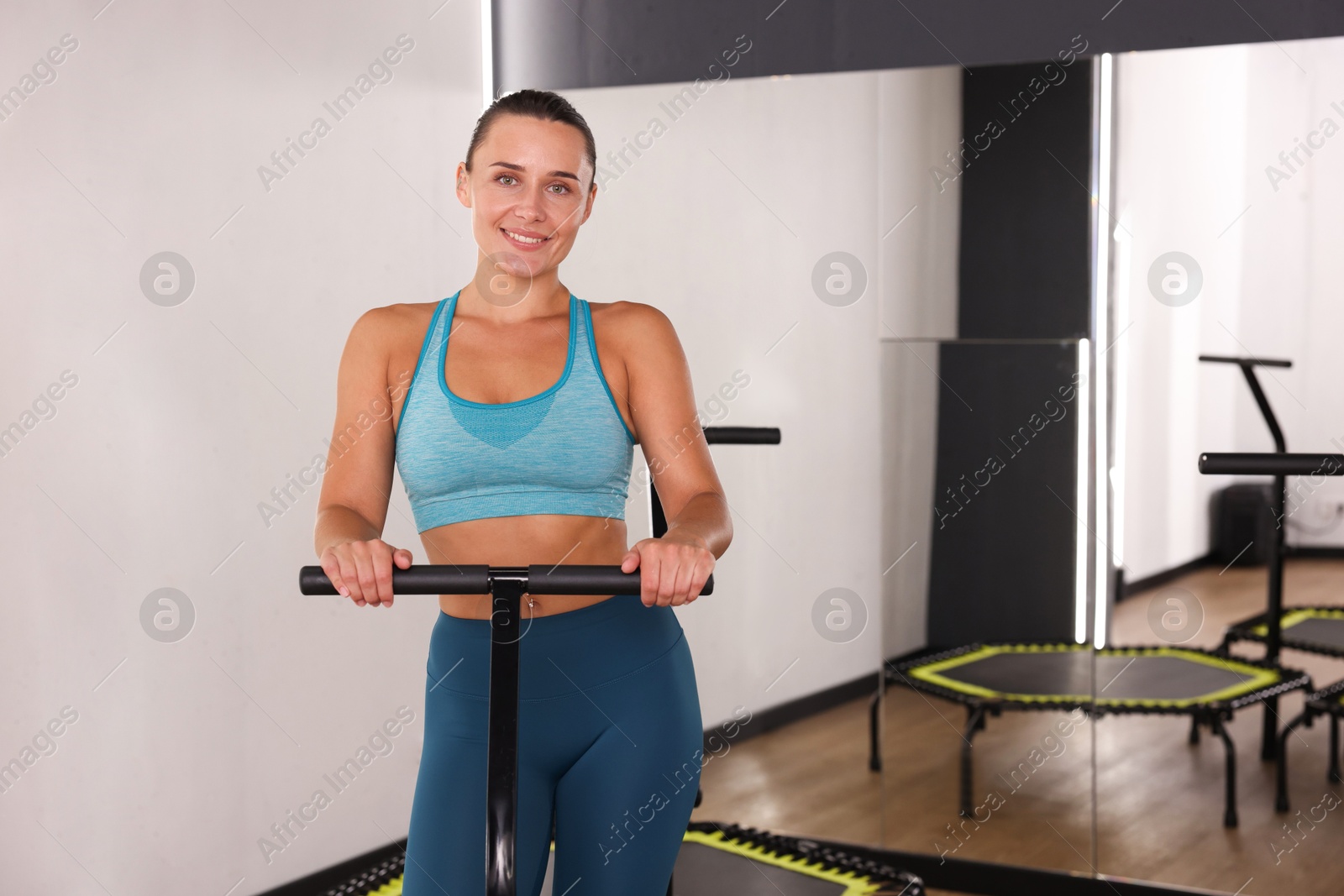 Smiling woman on mini exercise trampoline in fitness studio. Space for text Photo of Smiling woman on mini exercise trampoline in fitness studio. Space for text