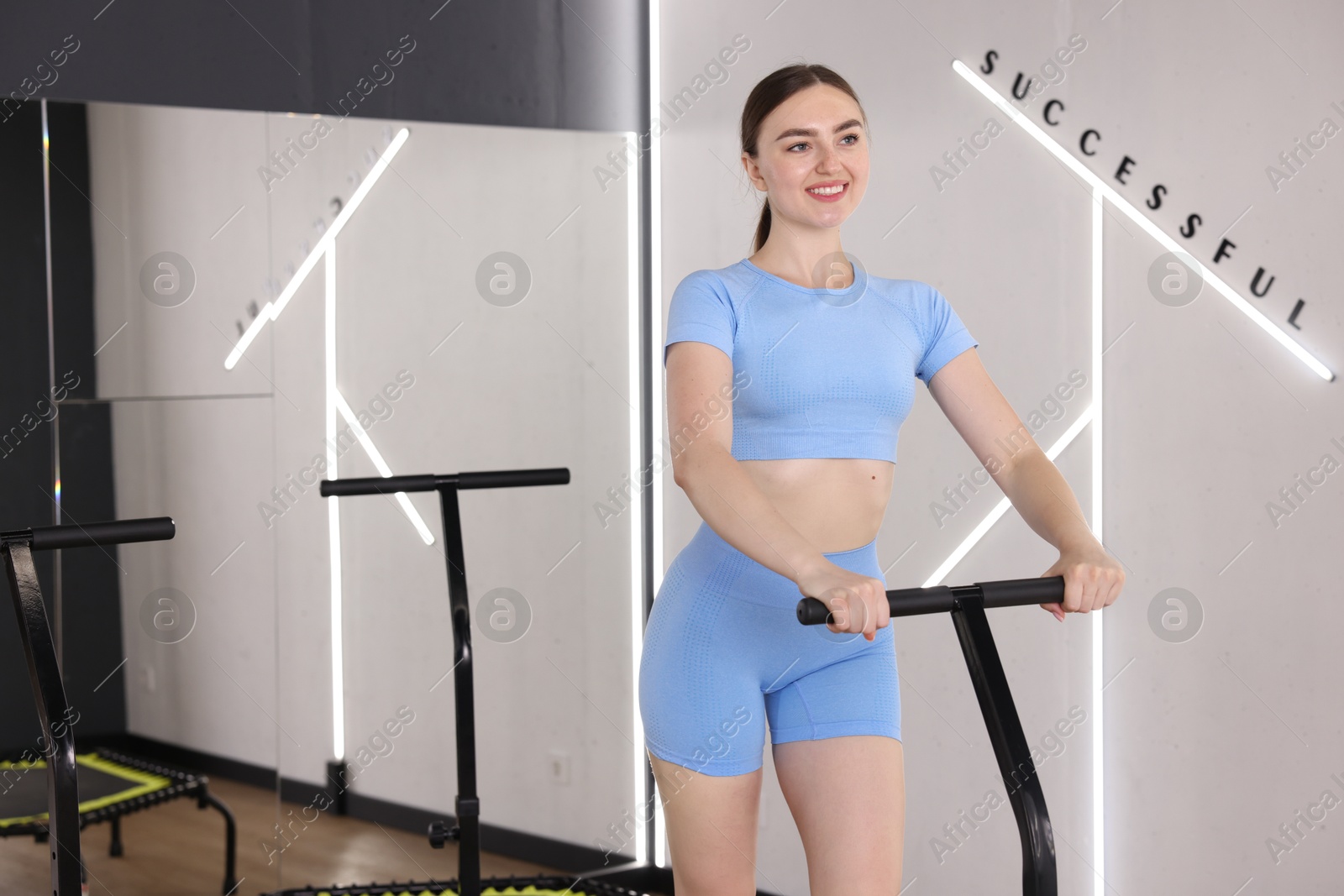 Smiling woman on mini exercise trampoline in fitness studio. Space for text Photo of Smiling woman on mini exercise trampoline in fitness studio. Space for text
