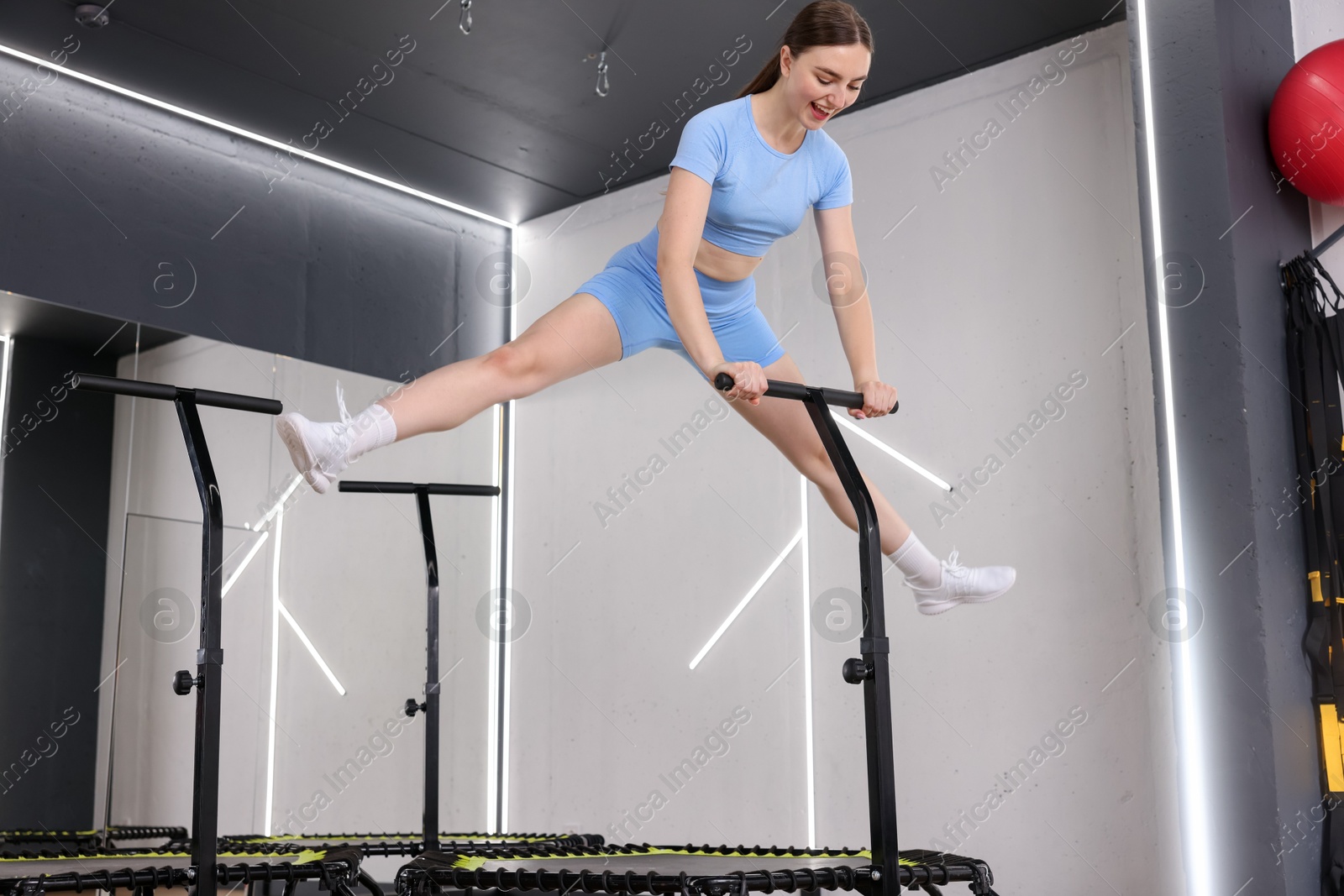 Photo of Smiling woman jumping on mini exercise trampoline in fitness studio, low angle view