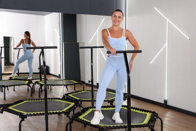 Photo of Smiling woman on mini exercise trampoline in fitness studio